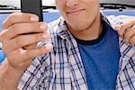 Mid section view of a young man holding a mobile phone