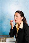 Side profile of a businesswoman applying lipstick on her lips