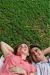 Erhöhte Ansicht eines jungen Paares liegen in einem Park und Lächeln
