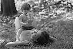 Portrait d'une jeune femme couchée sur l'herbe avec sa fille assise sur son ventre