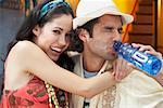 Close-up of a young woman smiling with a young man drinking water from a water bottle