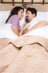 High angle view of a mid adult couple lying on the bed and looking at each other