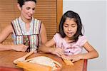 Girl preparing bread with her mother in the kitchen