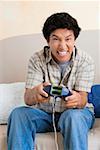 Close-up of a young man playing video game and smiling