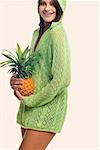 Portrait of a young woman standing and holding a pineapple