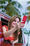 Jeune femme de prendre une photo avec un téléphone portable et souriant