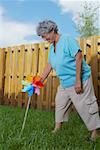 Side profile of a senior woman fixing a pinwheel in a lawn and smiling