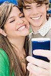 Close-up of a young woman and a teenage boy looking at a mobile phone and smiling