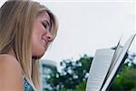 Side profile of a young woman reading a book and smiling