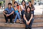 Two young men with three young women sitting on steps and smiling