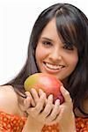 Portrait of a young woman holding a mango and smiling