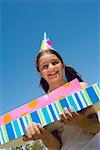 Portrait d'une jeune fille tenant des cadeaux d'anniversaire et souriant