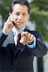 Portrait of a businessman talking on a mobile phone and pointing forward