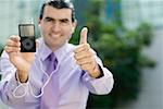 Portrait of a businessman showing an MP3 player and making a thumbs up sign