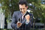 Businessman looking at a mobile phone and making a fist