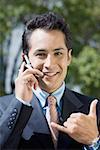 Portrait of a businessman talking on a mobile phone and showing call me gesture