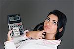 Close-up of a businesswoman holding a calculator and contemplating