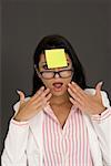 Close-up of a businesswoman looking shocked with an adhesive note in front of her forehead