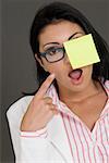 Close-up of a businesswoman looking shocked and pointing towards an adhesive note