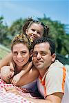 Portrait of a mid adult couple with their daughter lying on a picnic blanket