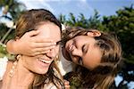 Close-up of a girl covering her mother's eyes