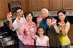 Portrait of a three generation family holding slices of a watermelon in the kitchen