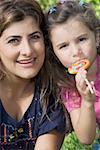 Portrait d'une femme adulte mid souriant avec sa fille manger un bonbon