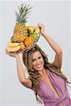 Portrait of a young woman holding a basket of assorted fruits and smiling