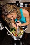 Vue grand angle d'une jeune femme, préparation de salade dans la cuisine