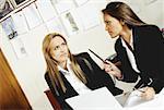 Deux femmes d'affaires parlant les uns aux autres dans un bureau