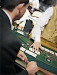 Mid section view of a casino worker dealing with playing cards on a gambling table