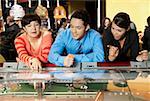 Femme mûre avec un homme adult moyen et une adolescente se penchant sur un casino