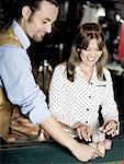 Casino worker arranging gambling chips on a gambling table with a young woman smiling beside him