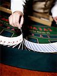 Mid section view of a casino worker's hand dealing with playing cards on a gambling table
