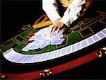 Mid vue en coupe d'un travailleur de casino traînant des cartes à jouer sur une table de jeu