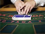 Close-up of a casino worker's hand shuffling playing cards on a gambling table