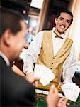 Rückansicht eines Reifen Mannes Spielkarten mit einem Kasino Worker vor ihm Stand zu halten