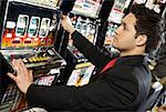 Side profile of a mid adult man playing on a slot machine