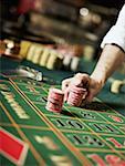 Close-up of a person's hand placing gambling chips on a gambling table