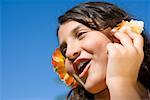 Close-up of a girl wearing flowers and listening to a conch shell