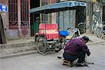 Vue arrière d'un mécanicien de réparer une cyclo-pousse, Pingyao, Province de Shaanxi, Chine