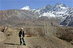 Young woman standing in front of mountains, Muktinath, Annapurna Range, Himalayas, Nepal