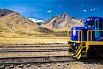 Train on a railroad track with a mountain range in the background, Puno, Peru