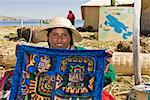 Portrait of a young woman showing a decorated blanket, Peru