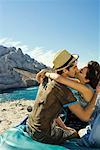 Man and woman sitting on car kissing.