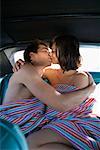 Man and woman on backseat of car kissing.