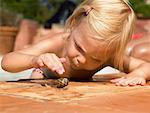 Little girl playing with a snail.