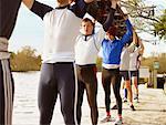 Crew with boat above heads on river bank.