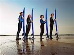 Four female surfers standing on a beach.