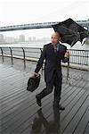 Business People Walking in Rain by Brooklyn Bridge, New York City, New York, USA